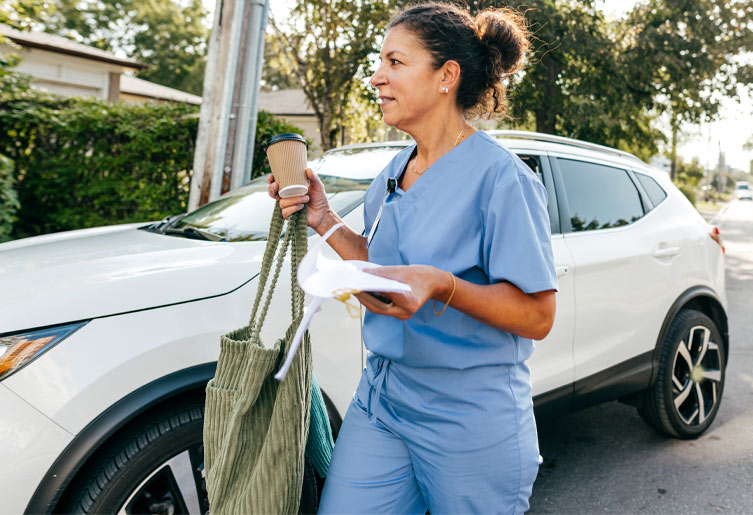 Medical Professional in front of while SUV holding a coffee cup