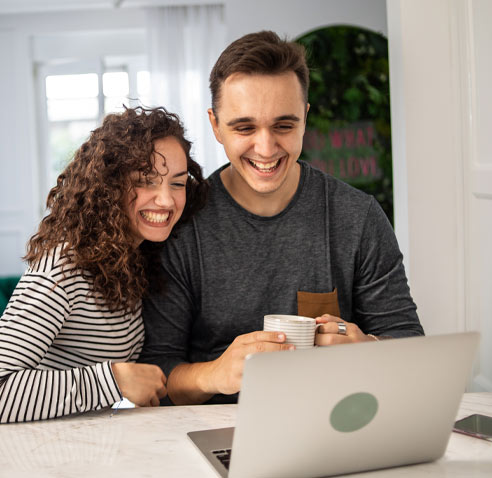 Woman and man holding a cup looking at laptop