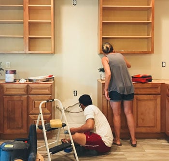 Couple installing kitchen cabinets