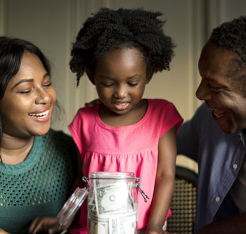 Mom, dad, and daughter looking at money in a jar