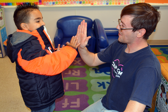 CAP COM volunteering high-fiving with child during Coats for Kids delivery day