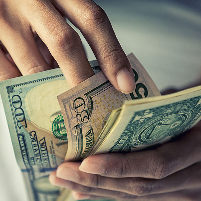 Person fingering through $50 and $100 bills