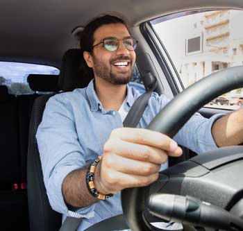 Man in blue shirt driving a car