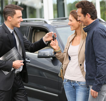 Couple at car dealer taking keys