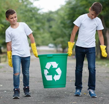 Two kids carrying a recycling bin