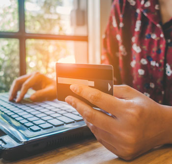 Person holding credit card and typing on laptop