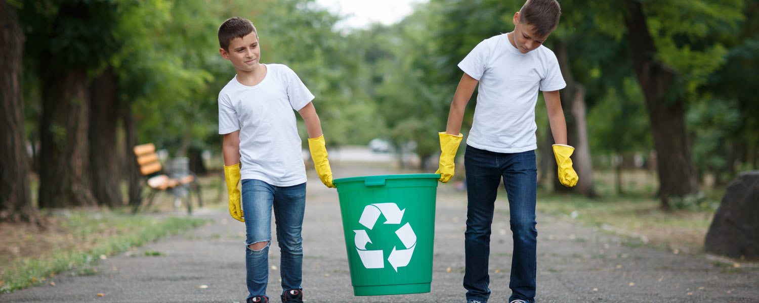 Two kids carrying a recycling bin