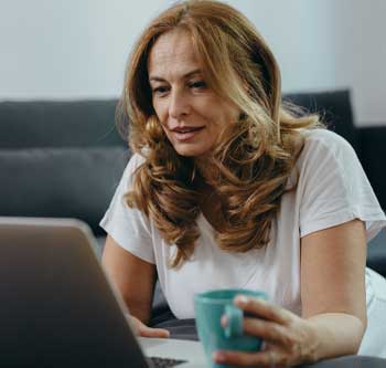 Woman looking at laptop and holding mug