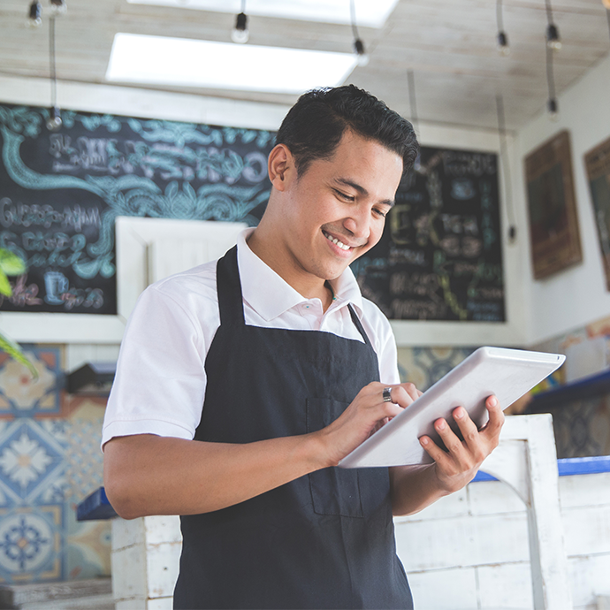 Man with apron looking at tablet