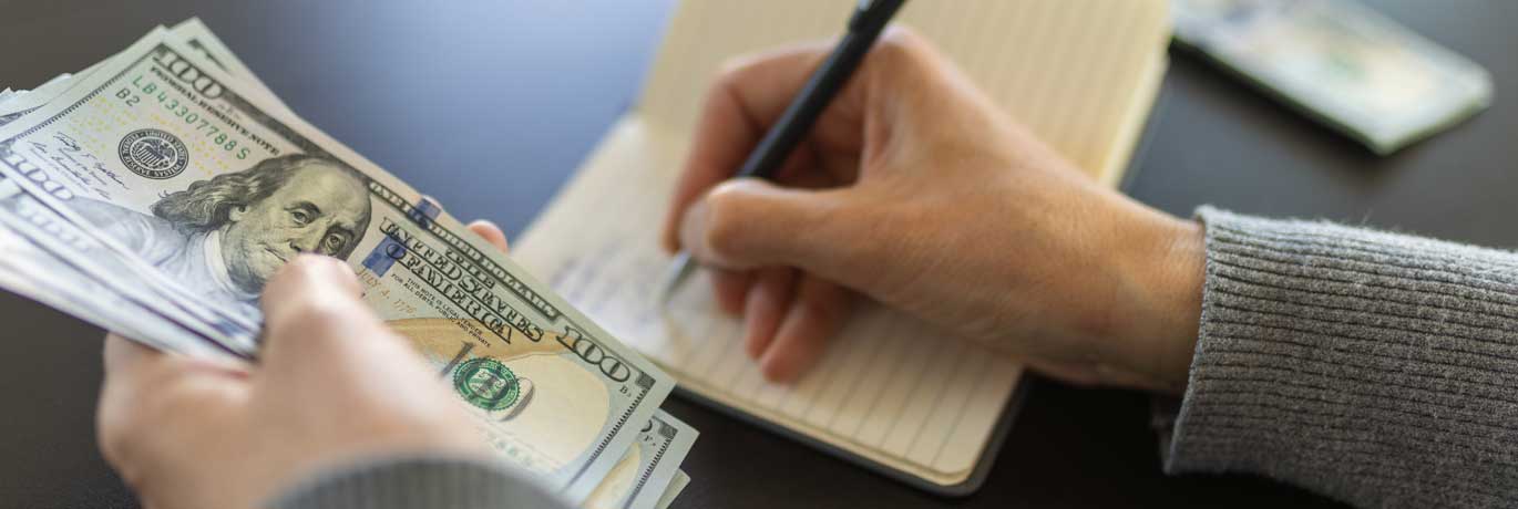 Person holding money and writing
