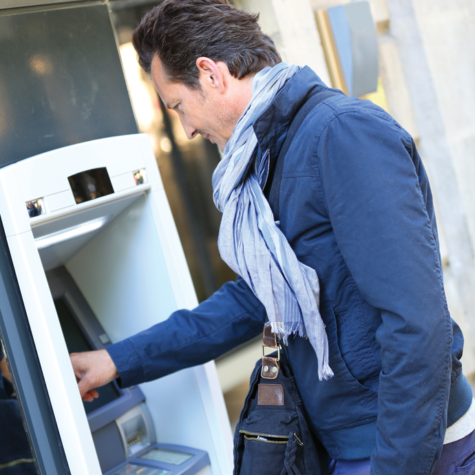 A man bundled up using an outside ATM.