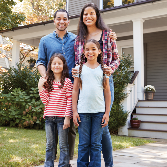 Family standing outside their house and smiling together