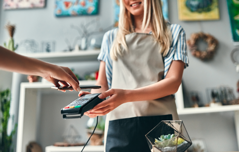 Woman holding card reader while someone scans phone