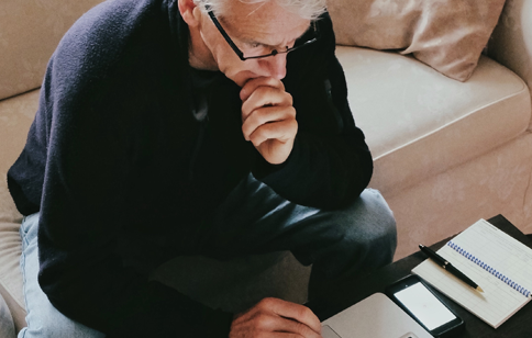 Man holding his chin while using laptop