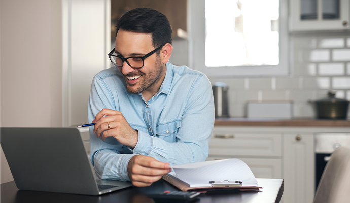 A man with glasses on using his laptop to do digital banking.