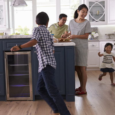 Two kids running around the kitchen while their parents make dinner