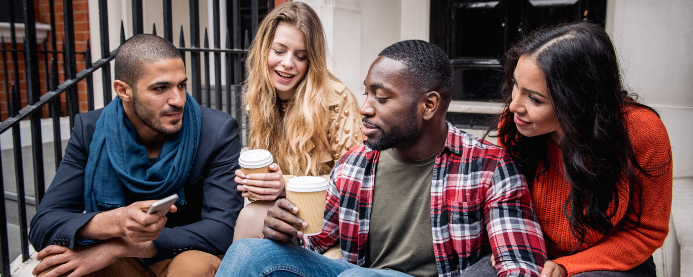 A group of thirty year olds chatting on a front stoop.