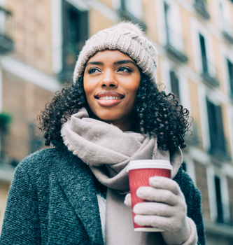 Woman bundled for the cold and holding a hot drink