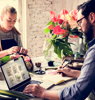 A man and woman florist making a floral arrangement on a table