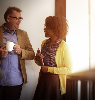 Coworkers chatting near a sunny window.