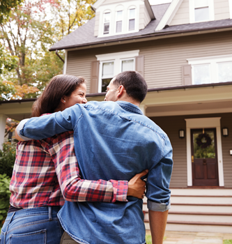 couple with arms around each other going towards house