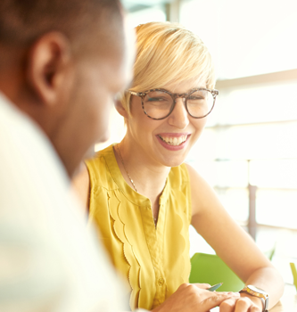 Blonde woman in glasses and yellow shirt smiling