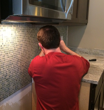 Man wearing red shirt fixing outlet in the kitchen