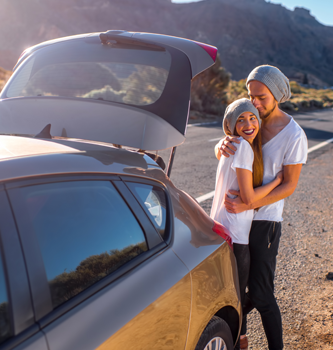 Man and woman in matching outfits cuddling ouside their car