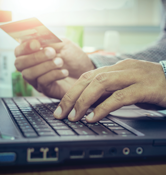 person holding a credit card while using laptop