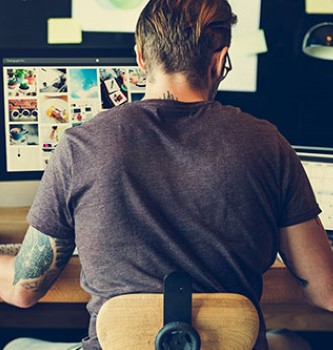 Man with several tattoos working on his computer