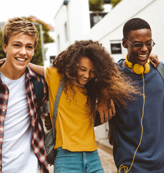 A trio of young adults walking together and laughing.