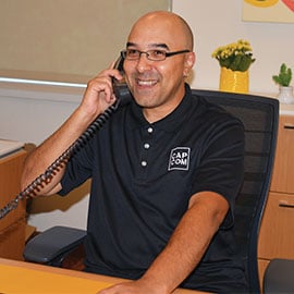 Dan G. a member relationship office, sitting at his desk helping a member on the phone.