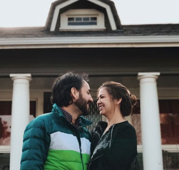 Smiling couple in front of a home